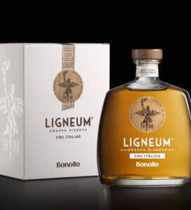 Bottiglia di Ligneum Cru Italiae di Bonollo 1908 con astuccio bianco, caratterizzata da un design elegante e dettagli dorati, su sfondo nero.