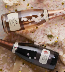 Bottiglie di Spumante Brut Rosé Carpineto tra petali e coriandoli rosa, ideale per brindisi eleganti e forniture HoReCa di alta gamma.